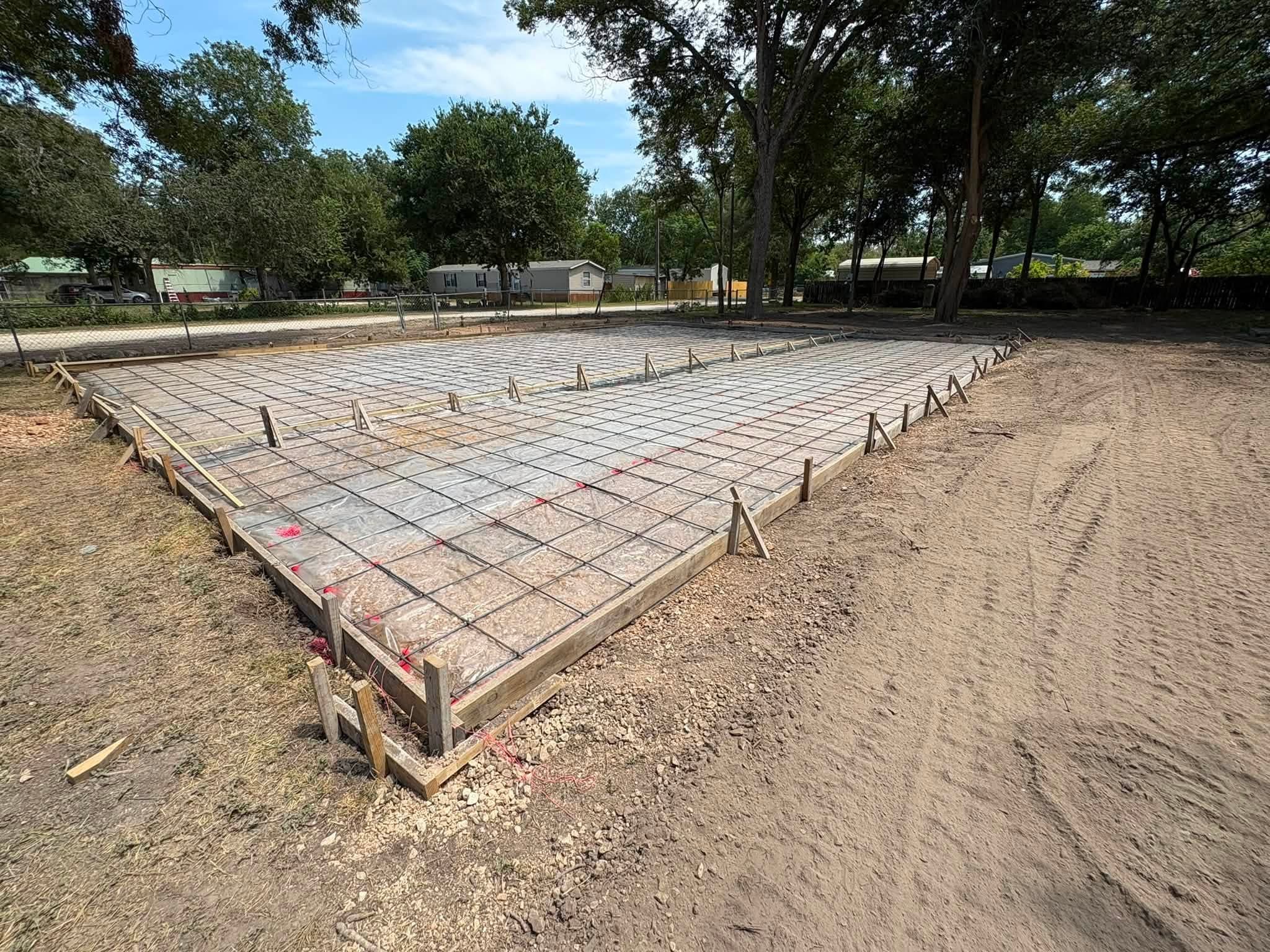 Slab forms with vapor barrier and steel reinforcement set before the pour in Seguin, TX
